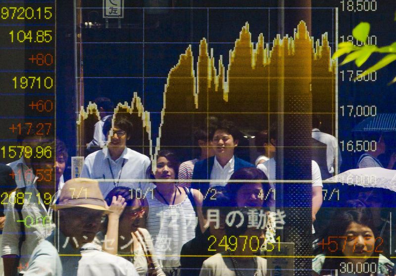 © Reuters. People are reflected in board displaying market indices in Tokyo