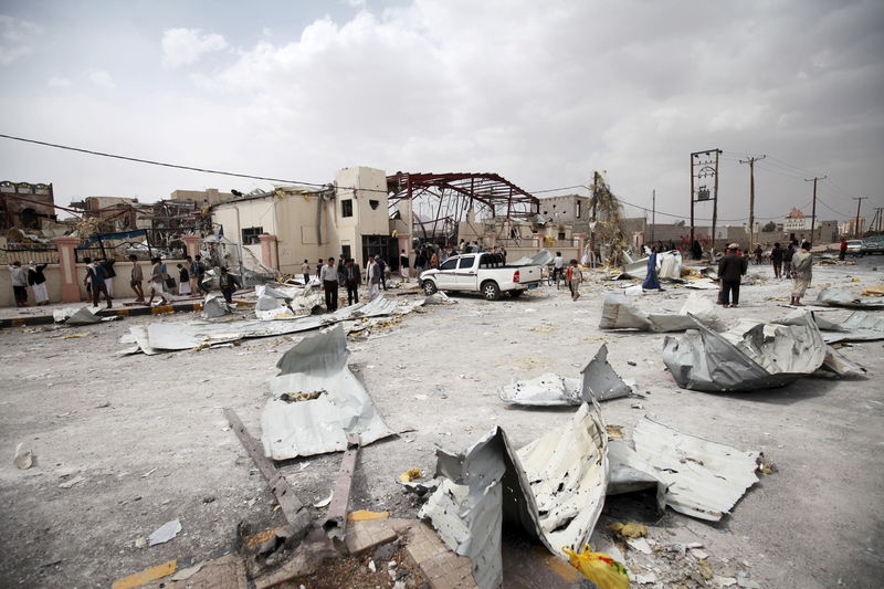 © Reuters. People walk among the remains of a wedding hall destroyed by a Saudi-led air strike in Sanaa