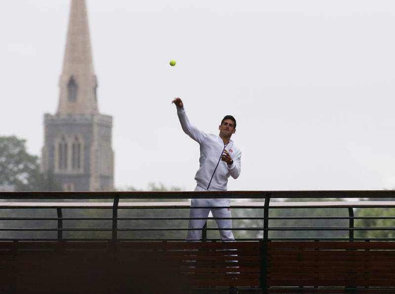 © Reuters. Novak Djokovic of Serbia throws balls at fans after he won his Men's Singles Final match against Roger Federer of Switzerland at the Wimbledon Tennis Championships in London