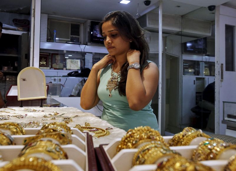 © Reuters. Женщина примеряет золотое ожерелье на рынке в Мумбаи