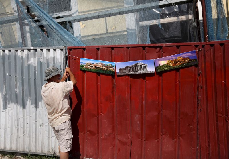 © Reuters. A street vendor hangs paintings depicting the Acropolis for sale at the Monastiraki area in Athens 