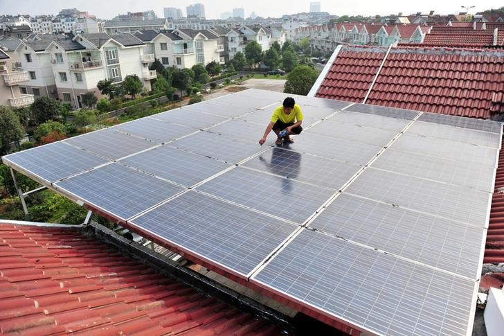 © Reuters. Trabalhador inspeciona painéis solares no teto de um edifício residencial em Yichang, na provícia chinesa de Hubei