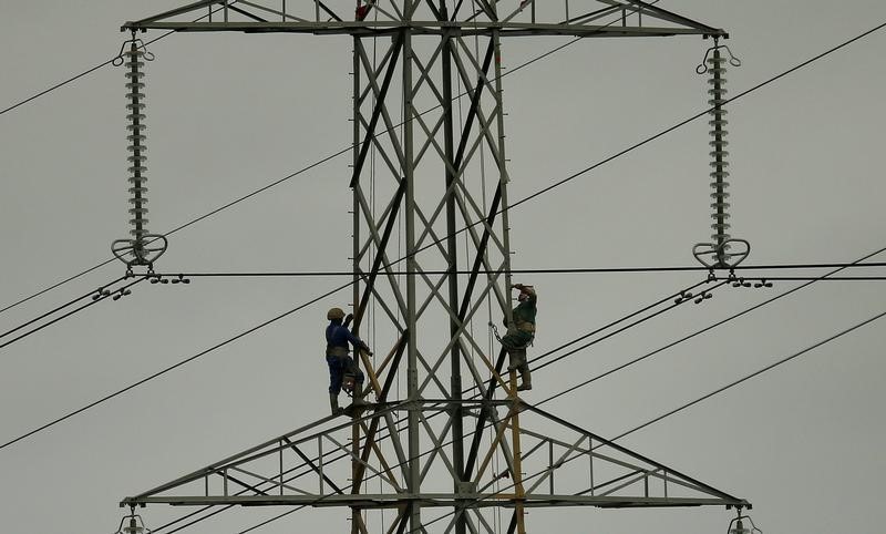 © Reuters. Workers paint an electricity pylon near Lymm, northern England