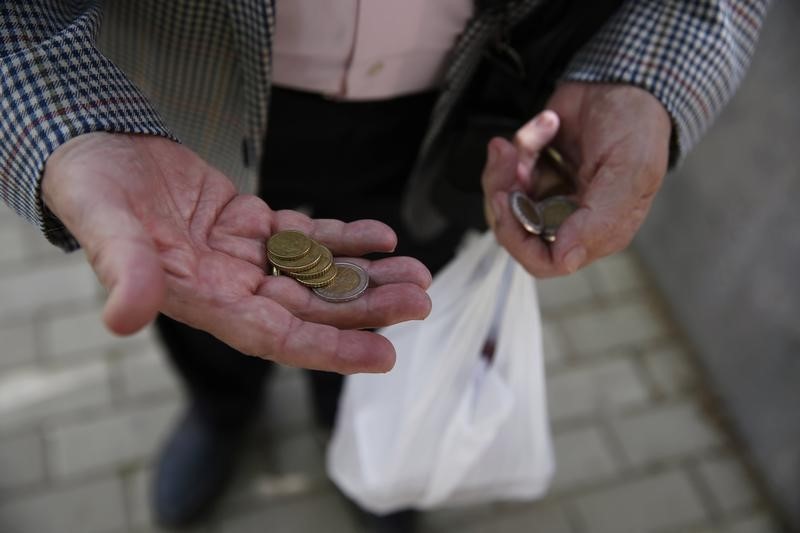 © Reuters. Gomez Gamallo counts his coins to buy a newspaper before his weekly lunch with one of his four children in Madrid