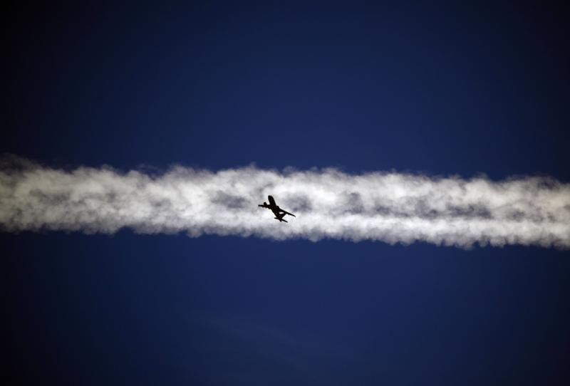 © Reuters. An aeroplane flies underneath the jet stream of another aircraft above the Italian city of Padova