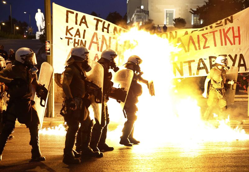 © Reuters. Riot police stand amongst flames from petrol bombs thrown by a small group of anti-establishment demonstrators in Athens