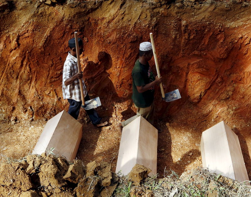 © Reuters. File photo of workmen walking among coffins in a mass grave of unidentified Rohingya remains found at a traffickers camp in Wang Kelian, at a cemetery near Alor Setar, Malaysia