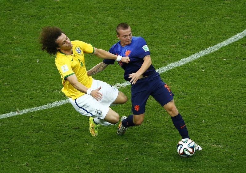 © Reuters. Brazil's Luiz is challenged by Clasie of the Netherlands during their 2014 World Cup third-place playoff at the Brasilia national stadium in Brasilia 