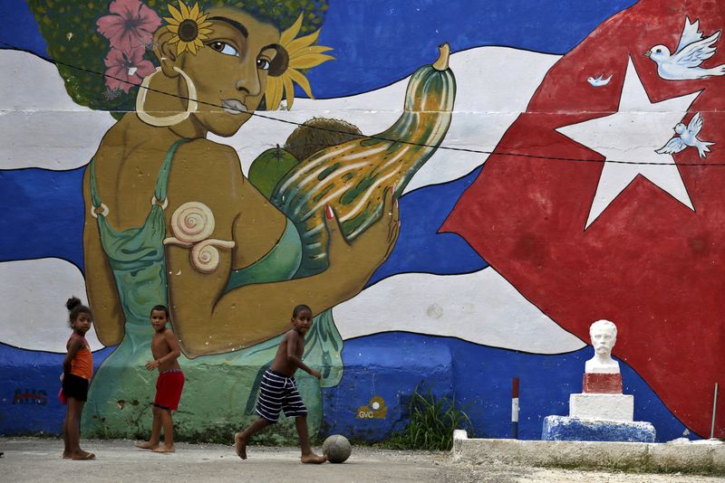 © Reuters. Crianças jogam bola em frente a um grafite da bandeira cubana em Havana