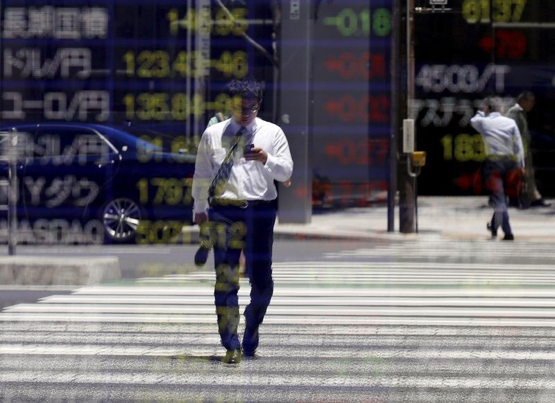 © Reuters. Man is reflected on a stock quotation board outside a brokerage in Tokyo