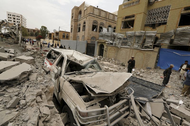 © Reuters. Houthi militants and people gather at the site of a Saudi-led air strike in Yemen's capital Sanaa