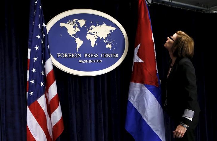 © Reuters. Funcionária do Centro de Imprensa Estrangeira de Washington arruma bandeiras dos EUA e de Cuba antes de entrevista coletiva em Washington