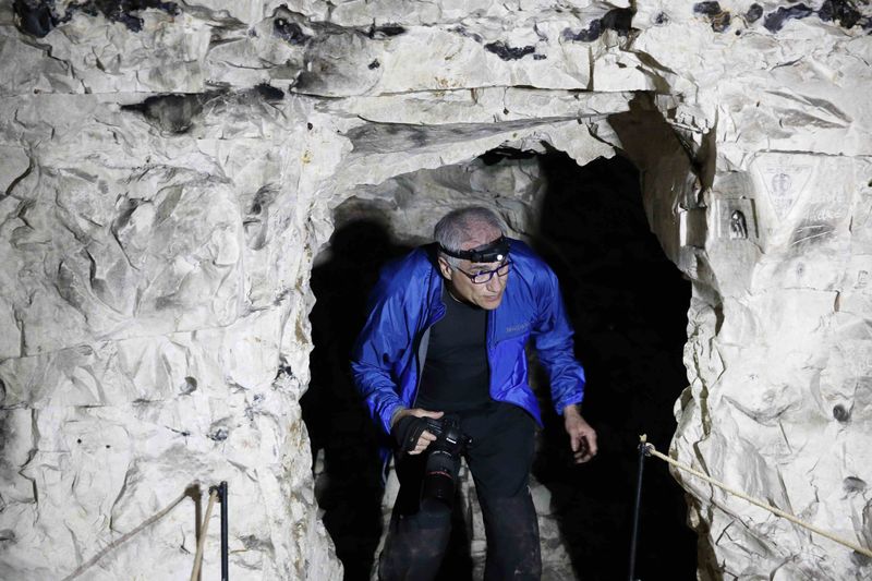 © Reuters. Jeffrey Gusky, a US medic and photographer, walks in underground caves in underground caves accessible by small spiral stairs in the village's church at Bouzincourt