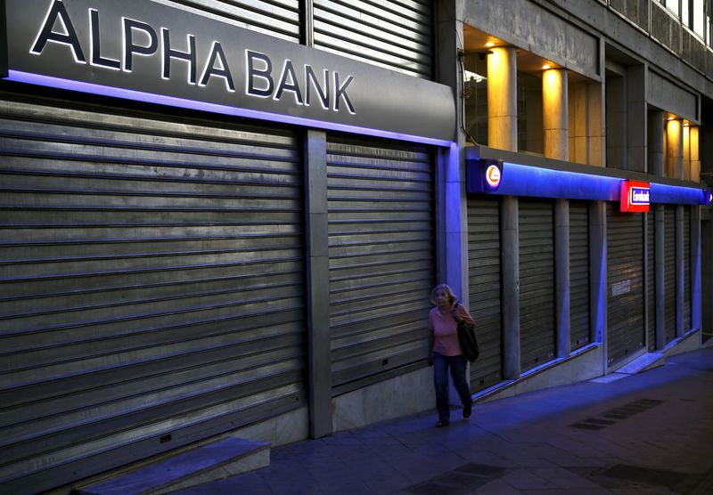 © Reuters. Woman walks by bank branches in Athens