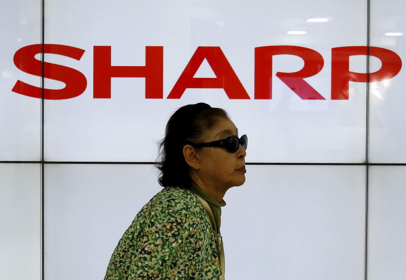 © Reuters. A woman walks past Sharp Corp's liquid crystal display monitors showing a company logo in Tokyo