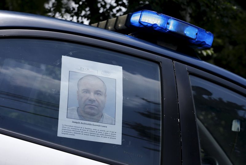 © Reuters. A police vehicle is seen a poster with a photo of drug lord Joaquin "El Chapo" Guzman offering a reward of 60 million Mexican pesos for information along a street in Mexico City