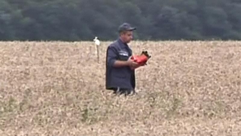 © Reuters. Still image from video shows a rescue worker carrying a flight data recorder at the crash site of Malaysia Airlines Flight MH17 in Hrabove