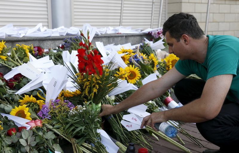 © Reuters. Homem coloca flores em embaixada da Holanda em Kiev um ano após queda do voo MH17