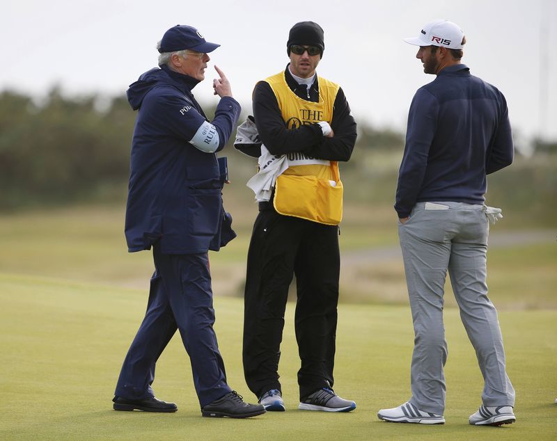 © Reuters. Johnson of the U.S. speaks to an official on the 15th green before play is suspended due to high winds during the second round of the British Open golf championship on the Old Course in St. Andrews, Scotland