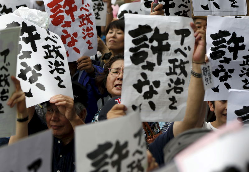 © Reuters. Protesters holding placards shout slogans during a rally against Japan's Prime Minister Shinzo Abe's administration and his security-related legislation outside the parliament building in Tokyo