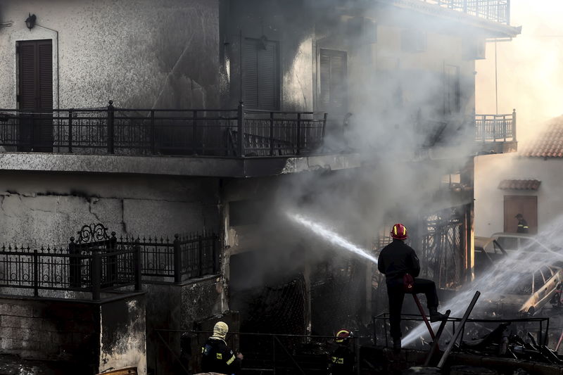 © Reuters. A firefighter tries to extinguish a fire at a building at the town of Neapoli in the region of Laconia in Peloponnese