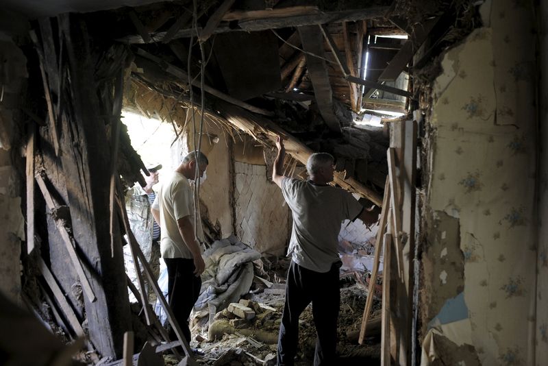 © Reuters. Local residents remove debris inside a damaged building, which according to locals was caused by recent shelling, in Avdiivka