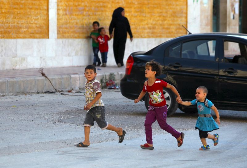 © Reuters. Children react as they run after hearing the sound of a Syrian fighter jet hovering over Idlib city, Syria