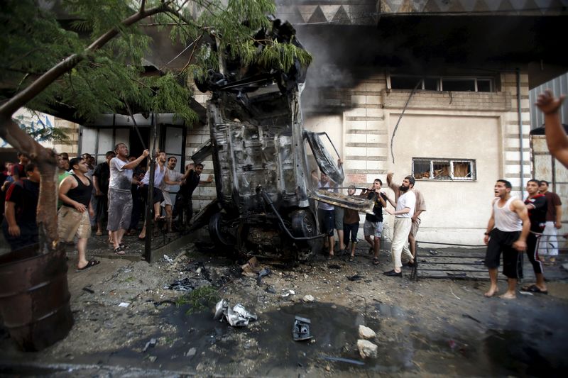 © Reuters. Palestinians inspect a car after it was blown up in Gaza City 