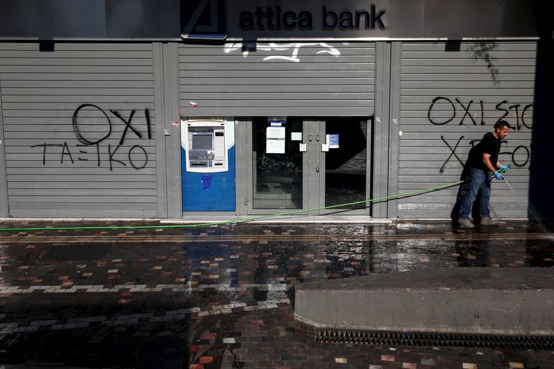 © Reuters. A man cleans the pavement in front a closed Attica Bank branch in Athens