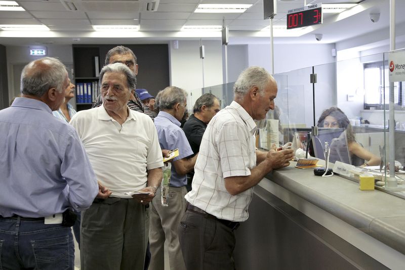 © Reuters. People make transactions at a counter inside a Piraeus Bank branch at the city of Iraklio in the island of Crete