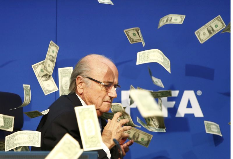 © Reuters. Banknotes are thrown at FIFA President Blatter as he arrives for a news conference after the Extraordinary FIFA Executive Committee Meeting at the FIFA headquarters in Zurich