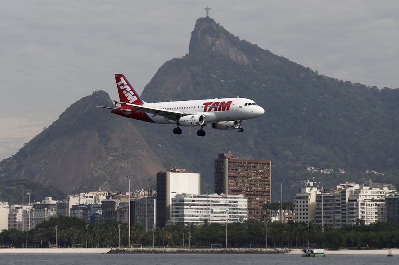 © Reuters. A TAM plane flies past the statue of Christ the Redeemer as it prepares to land at Santos Dumont airport in Rio de Janeir