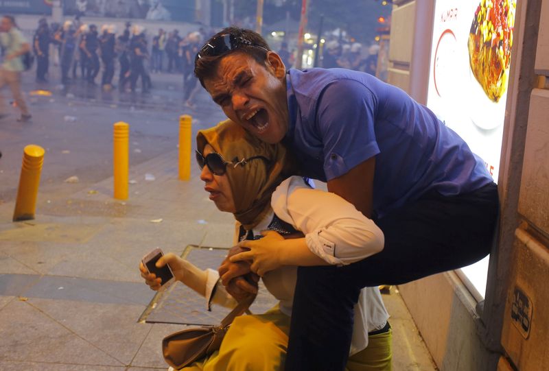 © Reuters. A couple, affected by tear gas used by riot police to disperse demonstrators, reacts in central Istanbul, Turkey,