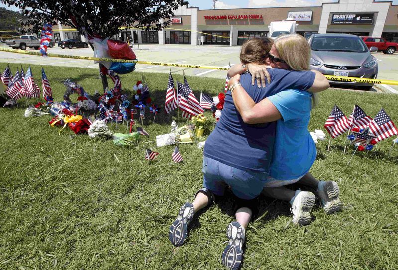 © Reuters. File photo of two friends hugging beside a growing memorial at the Armed Forces Career Center in Chattanooga