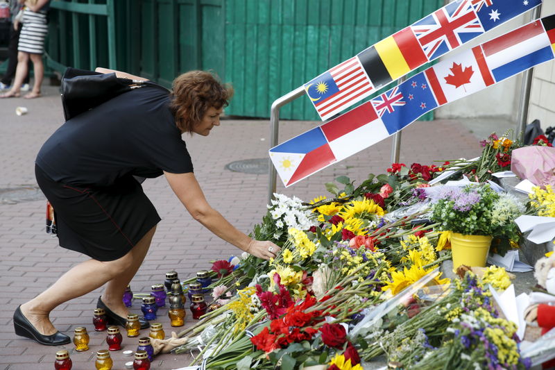 © Reuters. Mulher diante de flores que homenageiam mortos do voo MH17 em Kiev