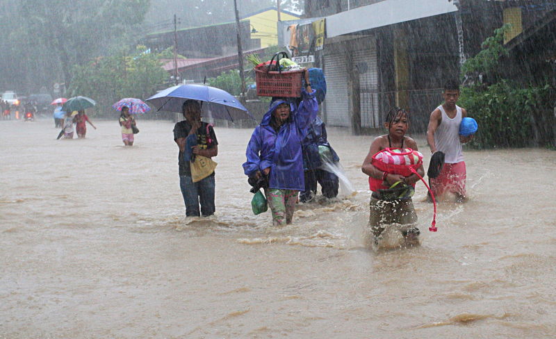 © Reuters. Moradores caminham por rua inundada depois que a tempestade tropical Linfa atingiu San Fernando