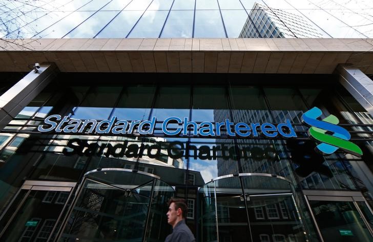 © Reuters. A man walks past the head office of Standard Chartered bank in the City of London