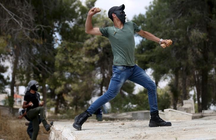 © Reuters. Palestinian protester throws a stone towards Israeli troops during clashes following a rally marking Nakba Day near Israel's Ofer Prison near Ramallah