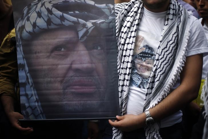 © Reuters. Palestinian Fatah supporters wear a T-shirt and hold a poster depicting late Palestinian leader Yasser Arafat during a rally marking the tenth anniversary of his death, in Gaza City