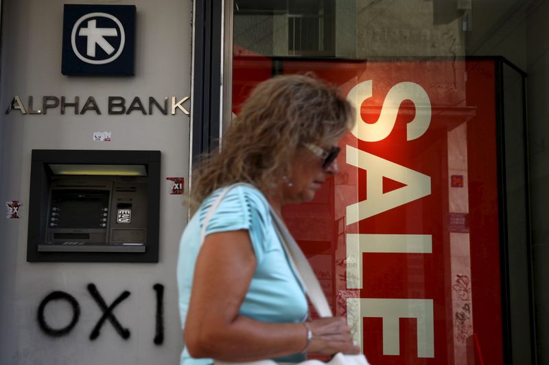 © Reuters. Mulher passa em frente a banco e loja anunciando promoção em Atenas