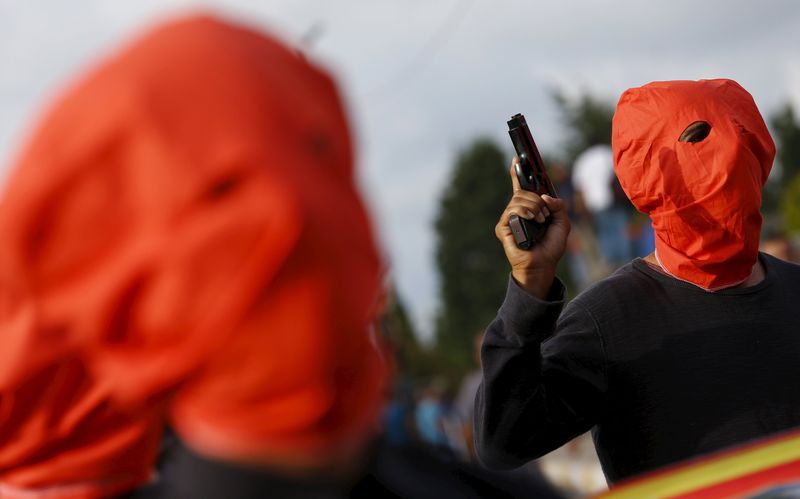 © Reuters. Homem armado acompanha outros que carregam os caixões com corpos das vítimas de um atentado ocorrido na segunda-feira