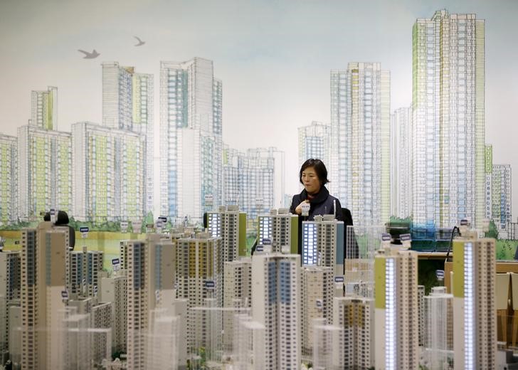 © Reuters. A visitor looks at a miniature model of an apartment complex which is currently under construction at its showroom in Seoul 