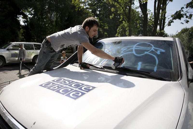 © Reuters. A demonstrator sprays graffiti on a OSCE vehicle during a protest in Donetsk