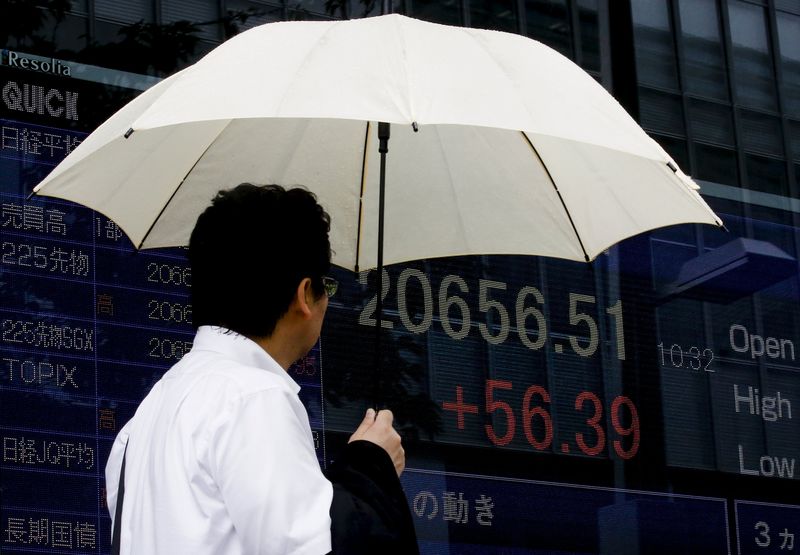 © Reuters. A man looks at a board displaying the Nikkei average in Tokyo