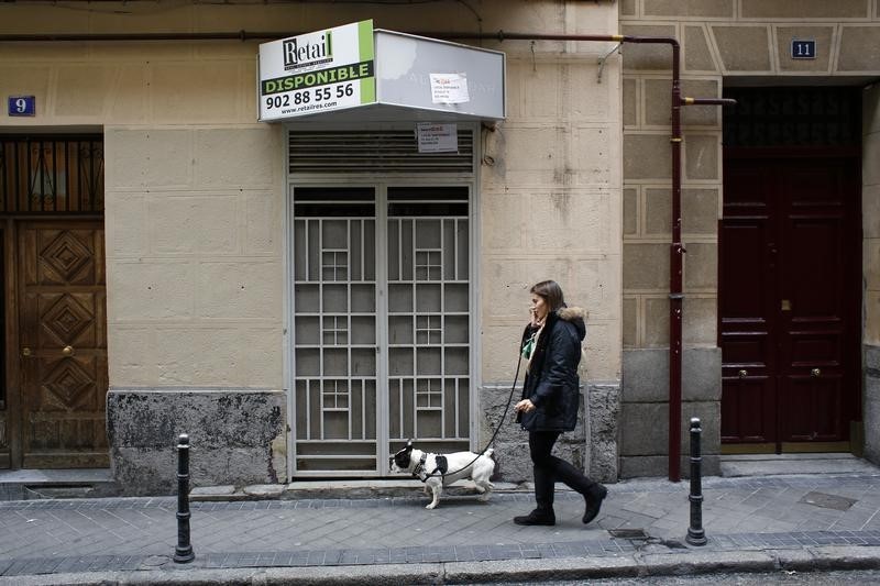 © Reuters. A woman walks past a closed down business in Madrid