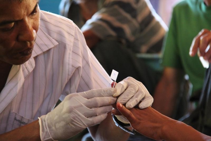 © Reuters. Un operatore sanitario del governo birmano effettua un test per la malaria a una donna.