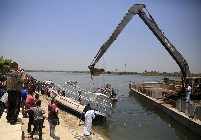 © Reuters. People gather along the banks as a crane raises a boat which had capsized on the River Nile, in the Warraq area of Giza, south of Cairo