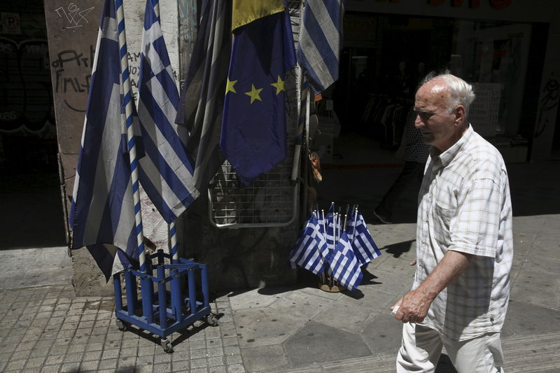 © Reuters. Homem em frente bandeiras da Grécia e da União Europeia, em Atenas