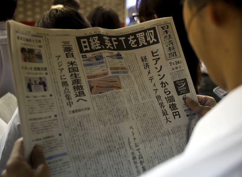 © Reuters. A man reads the front page of Japan's Nikkei newspaper reporting Japanese media group Nikkei's acquisition of the Financial Times from Britain's Pearson at a train station in Tokyo
