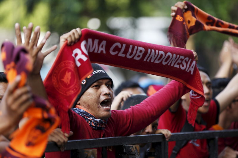 © Reuters. An Indonesian supporter of AS Roma football club cheers after the team arrived for a training session at  Gelora Bung Karno stadium in Jakarta